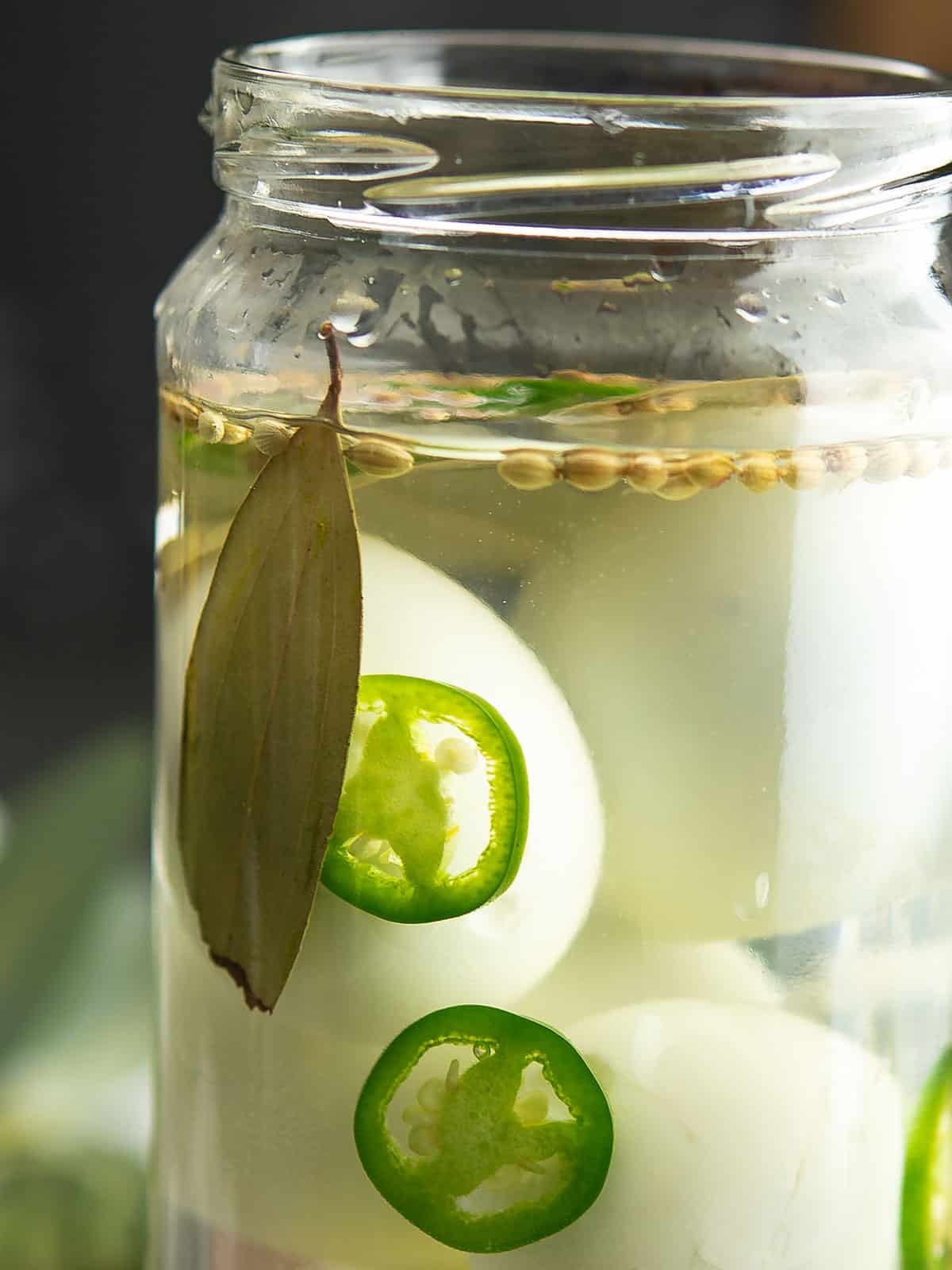 close up view of jalapeno pickled eggs on a jar