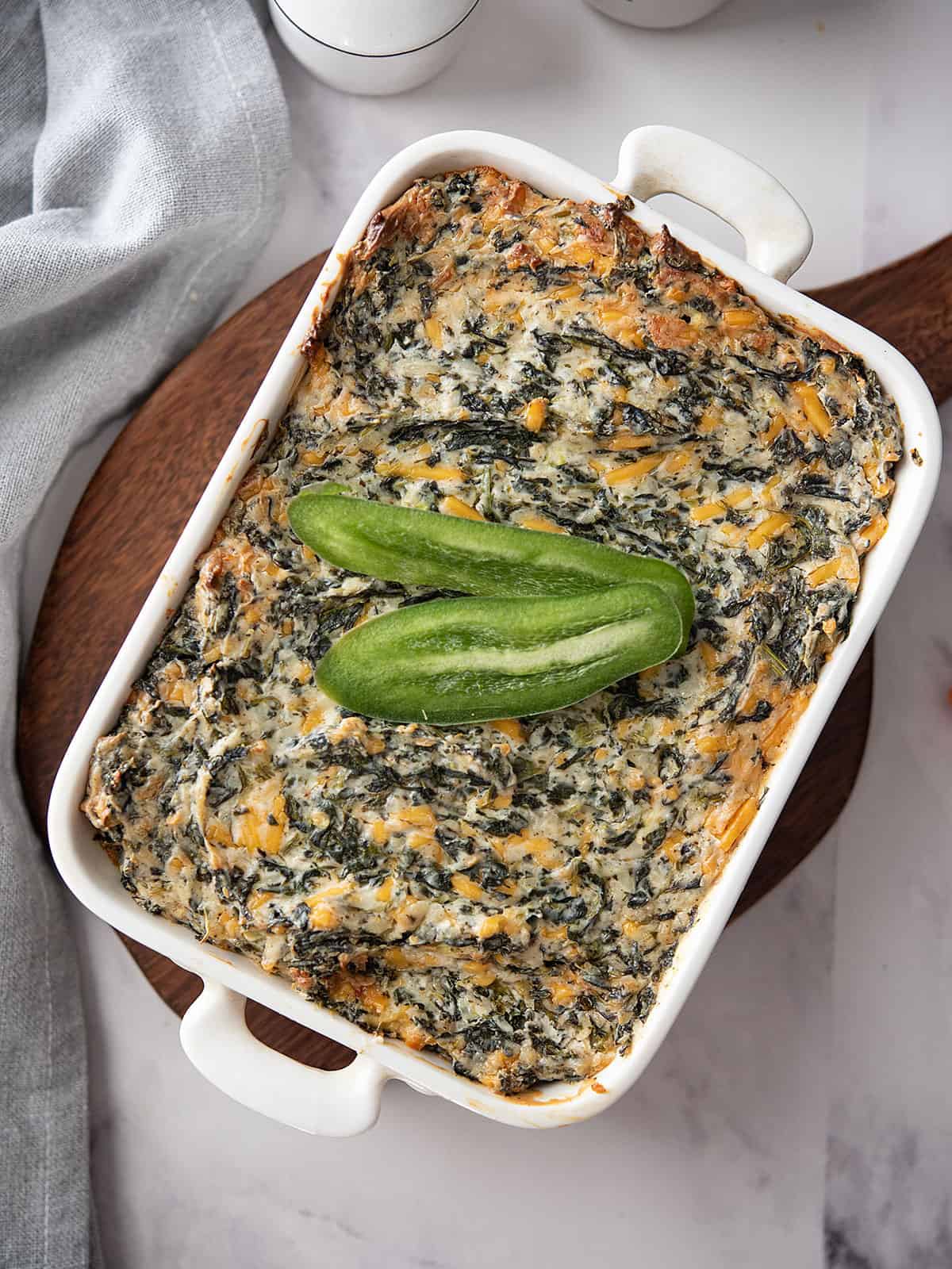 Baked jalapeno spinach dip served in a white dish with crispy edges.