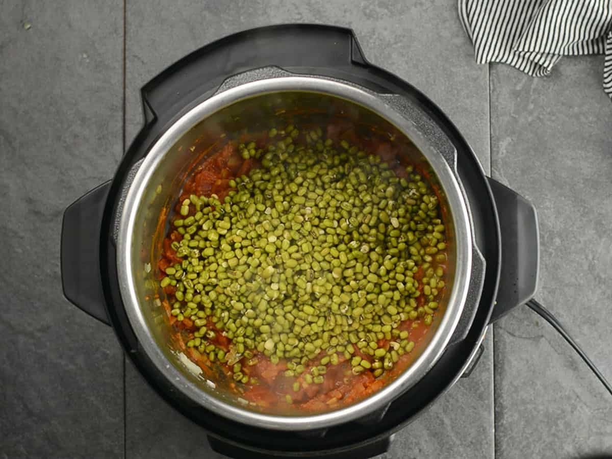 Adding soaked mung beans to the pot for cooking
