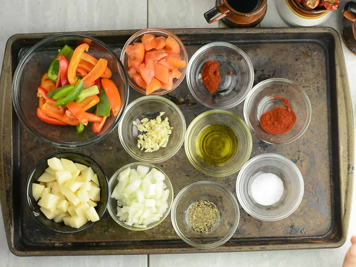 Fresh ingredients for Pepperonata including peppers, potatoes, onion, and garlic.