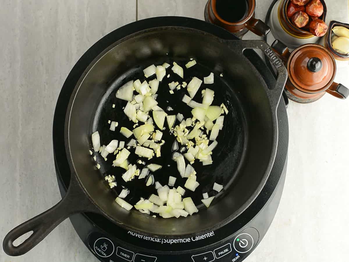 Sautéing garlic and onions in olive oil for Pepperonata.