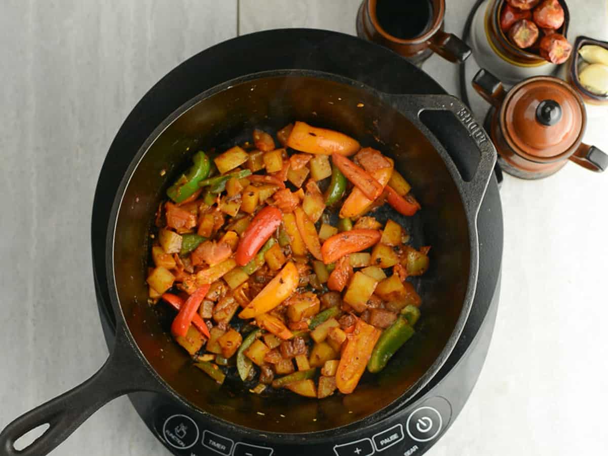 Mixing in sweet peppers and tomatoes into the Pepperonata mixture.