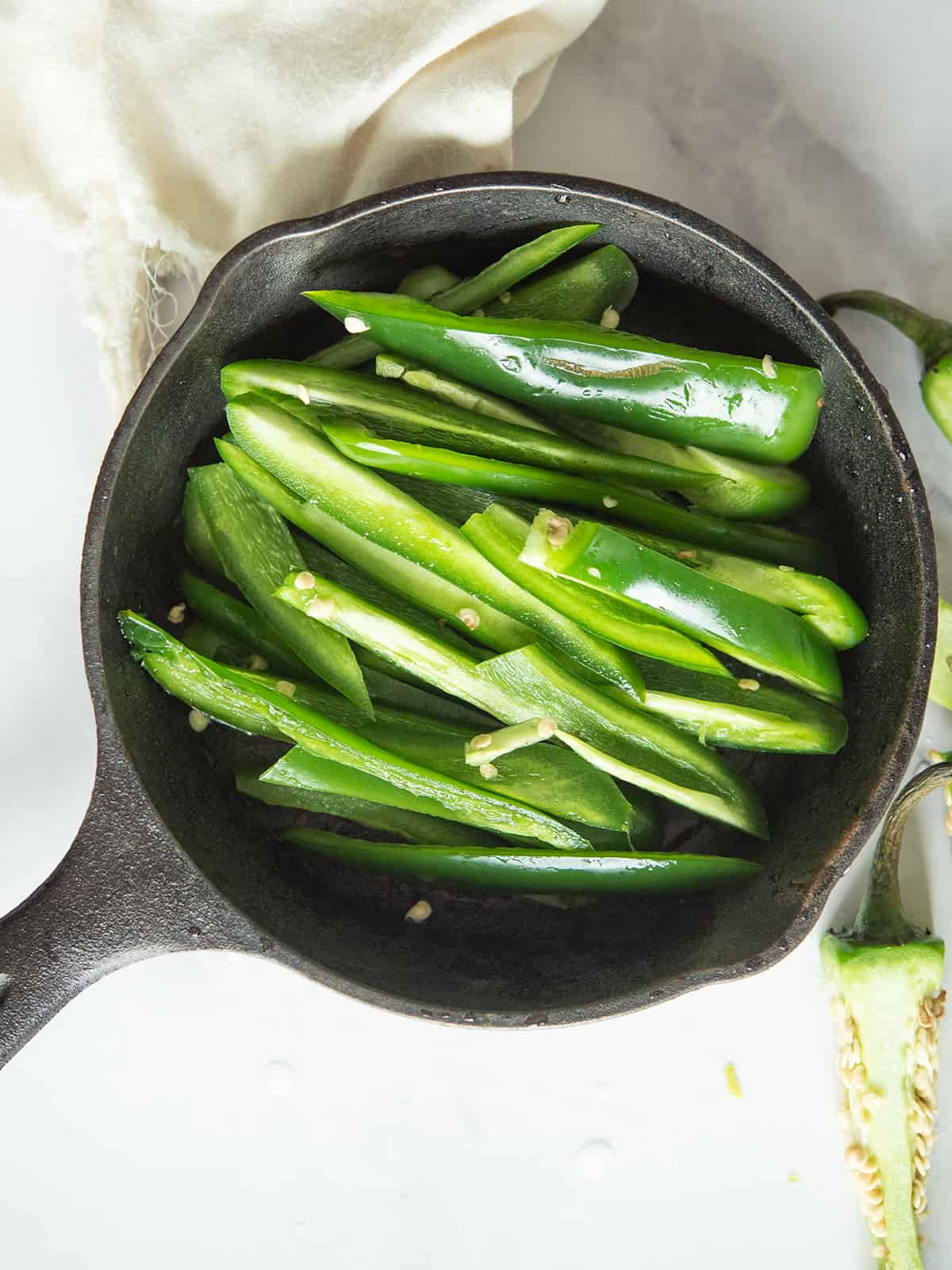 Mixing jalapeno strips with olive oil and spices in a bowl.