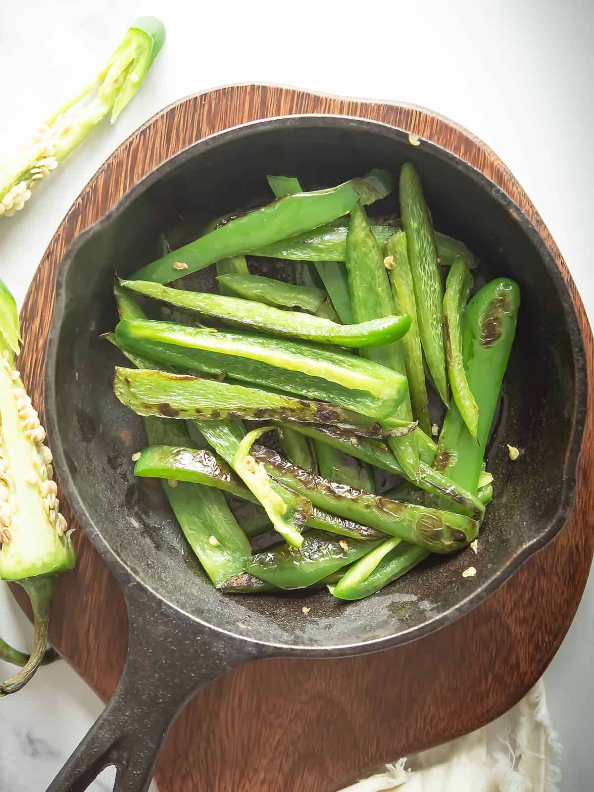 Golden brown sautéed jalapenos cooking in a skillet.