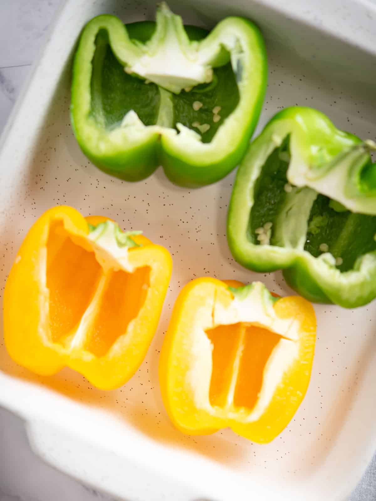 Halved bell peppers ready to be stuffed with seafood filling.