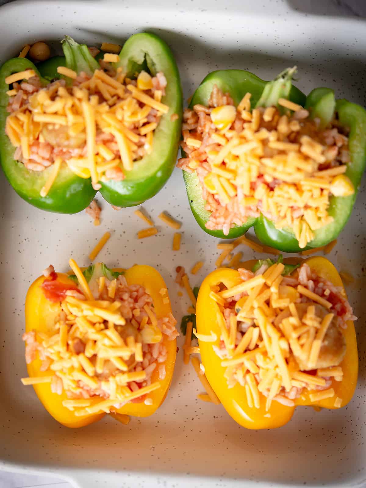 Stuffed bell peppers topped with cheese before baking