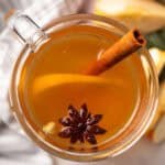 spiced apple cider served in a glass with lemon slices and the cool drink