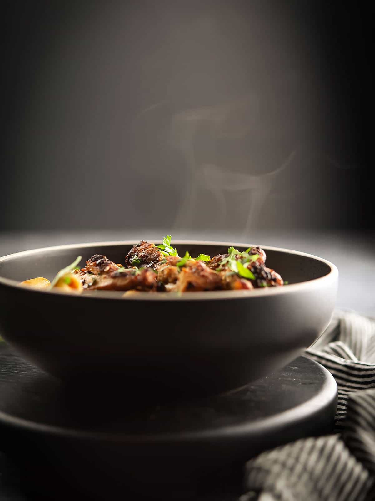 piping hot spicy chicken pasta in a black bowl over dinner table