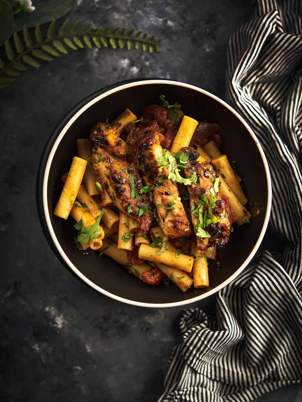 Delicious spicy chicken pasta served in a bowl with fresh herbs.