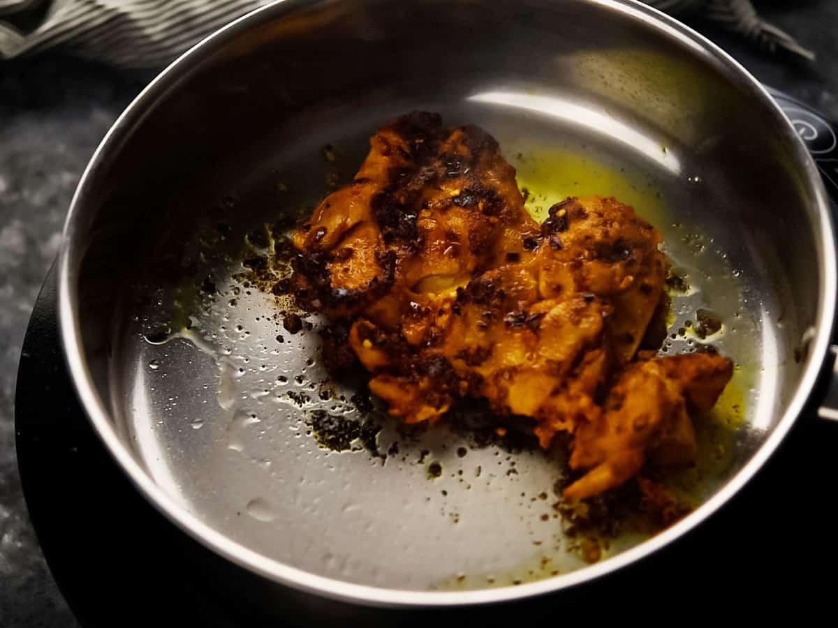 Marinated chicken thigh coated in spices while cooking.