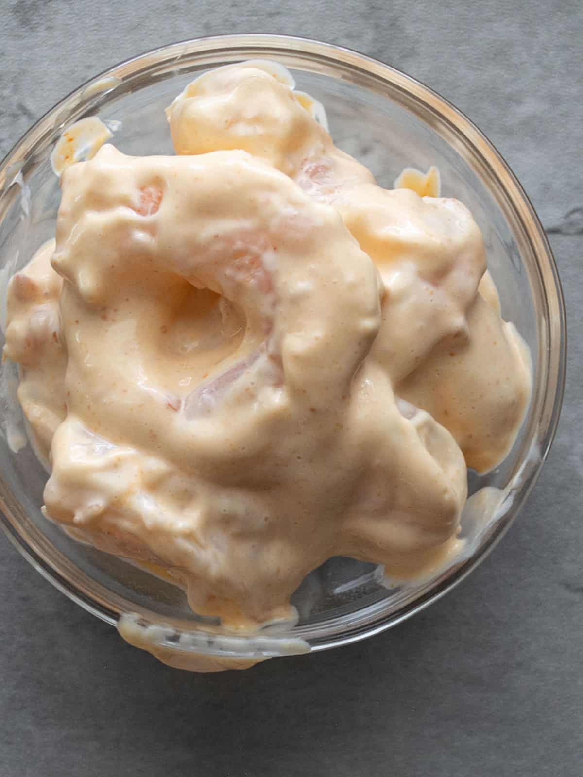 Mixing shrimp with mayo, lemon juice, and sriracha sauce in a bowl.
