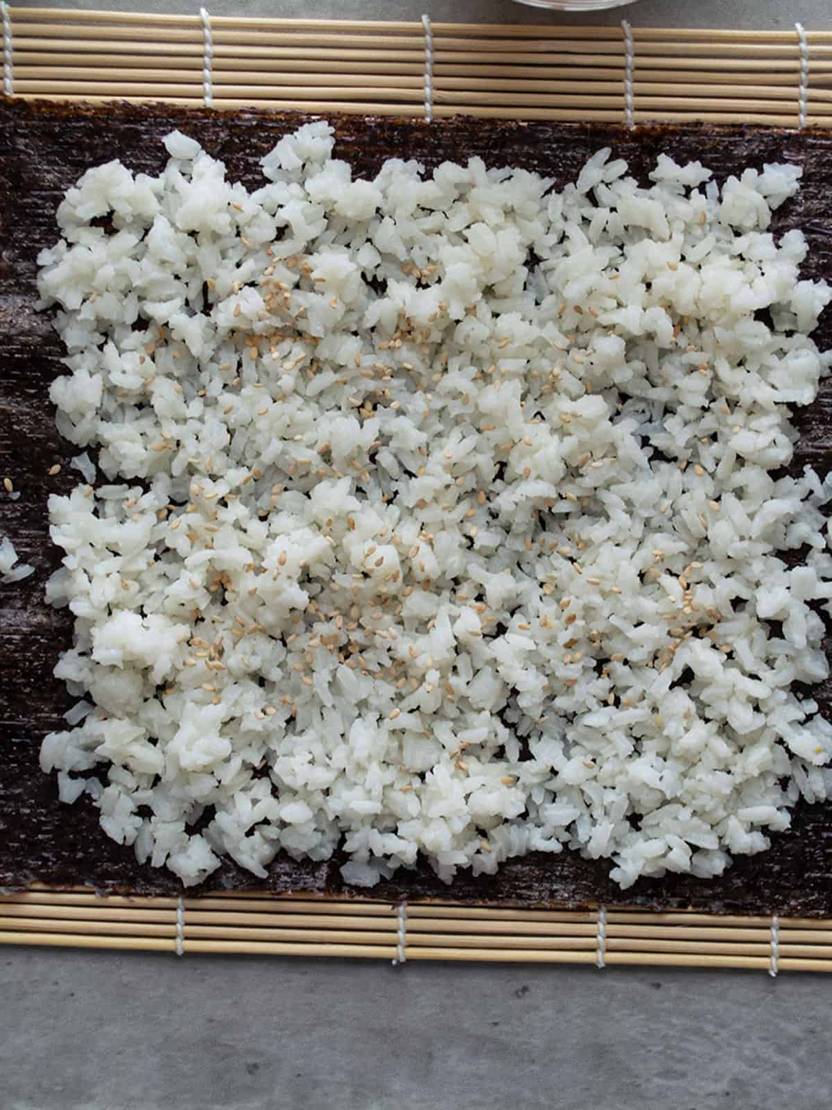 Spreading sushi rice on nori sheet for making spicy shrimp rolls.