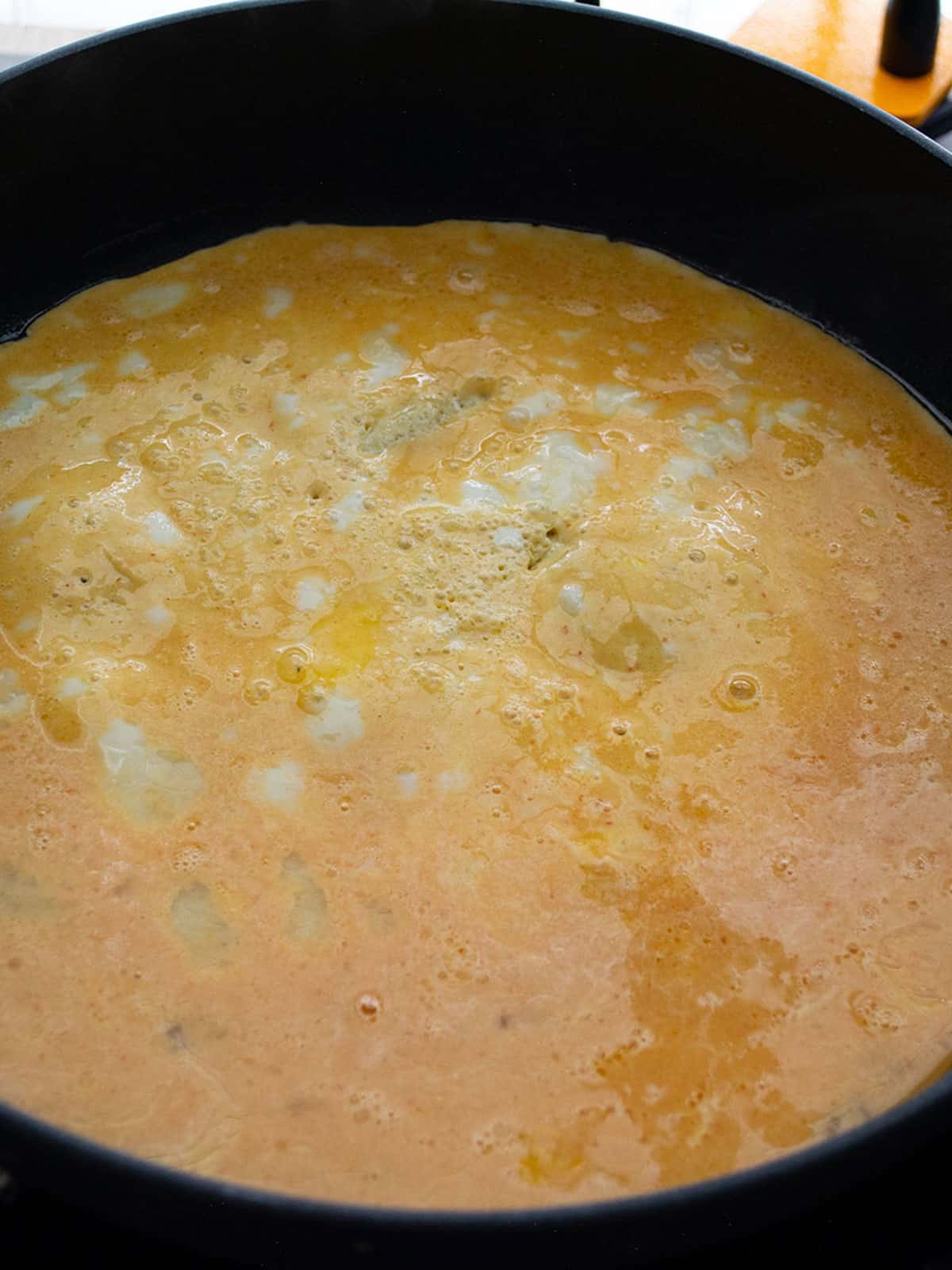 Pouring the egg mixture into the sizzling skillet.