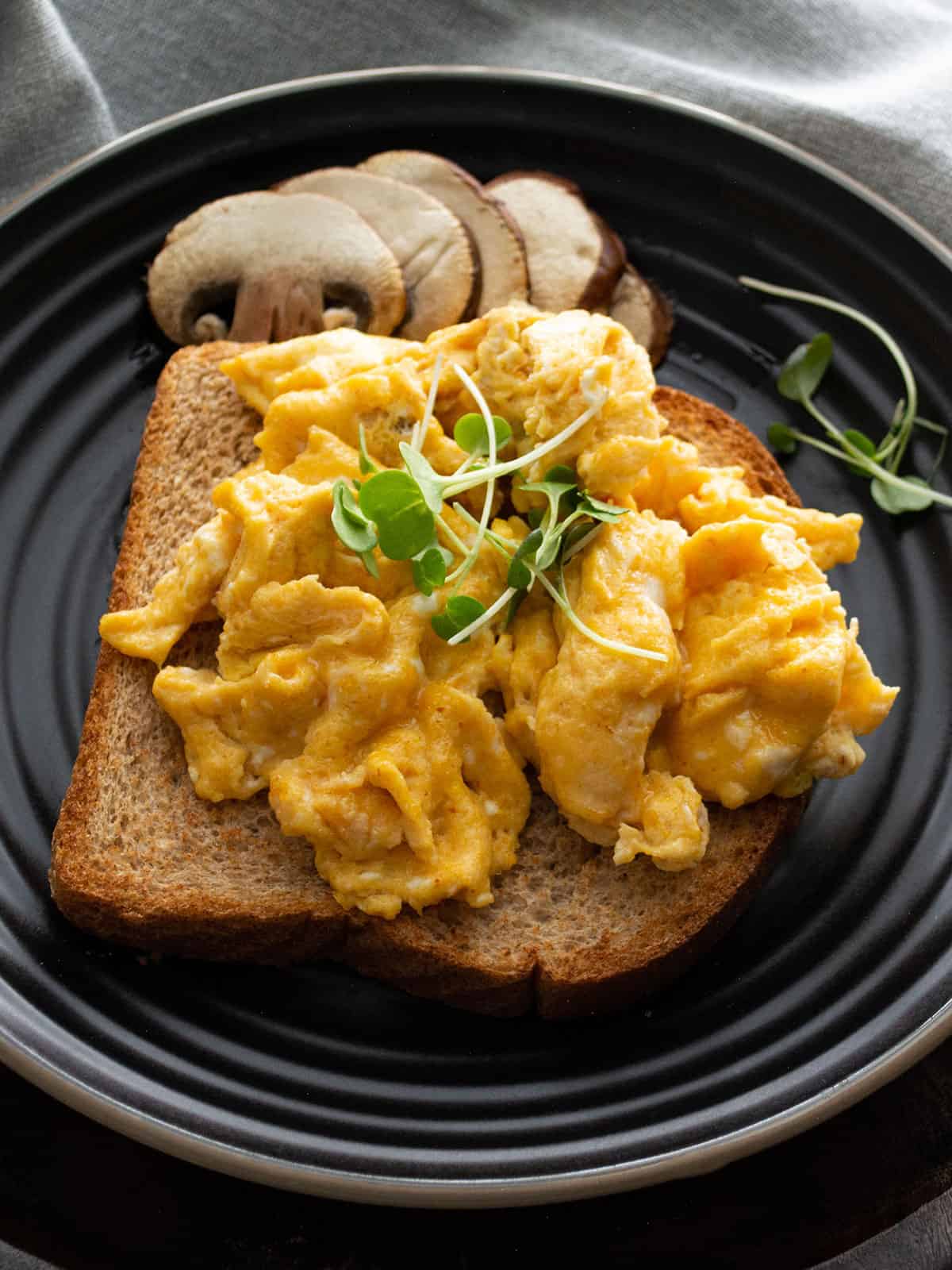 Sriracha scrambled eggs served on a plate with a sprinkle of herbs.