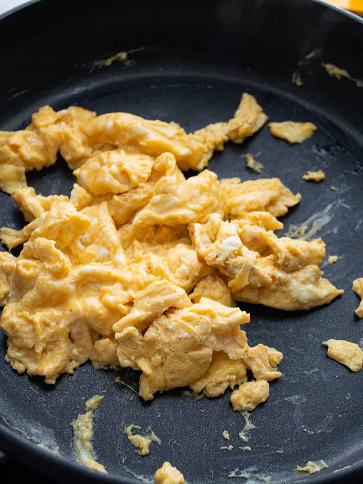 Stirring the scrambled eggs in the pan until creamy.