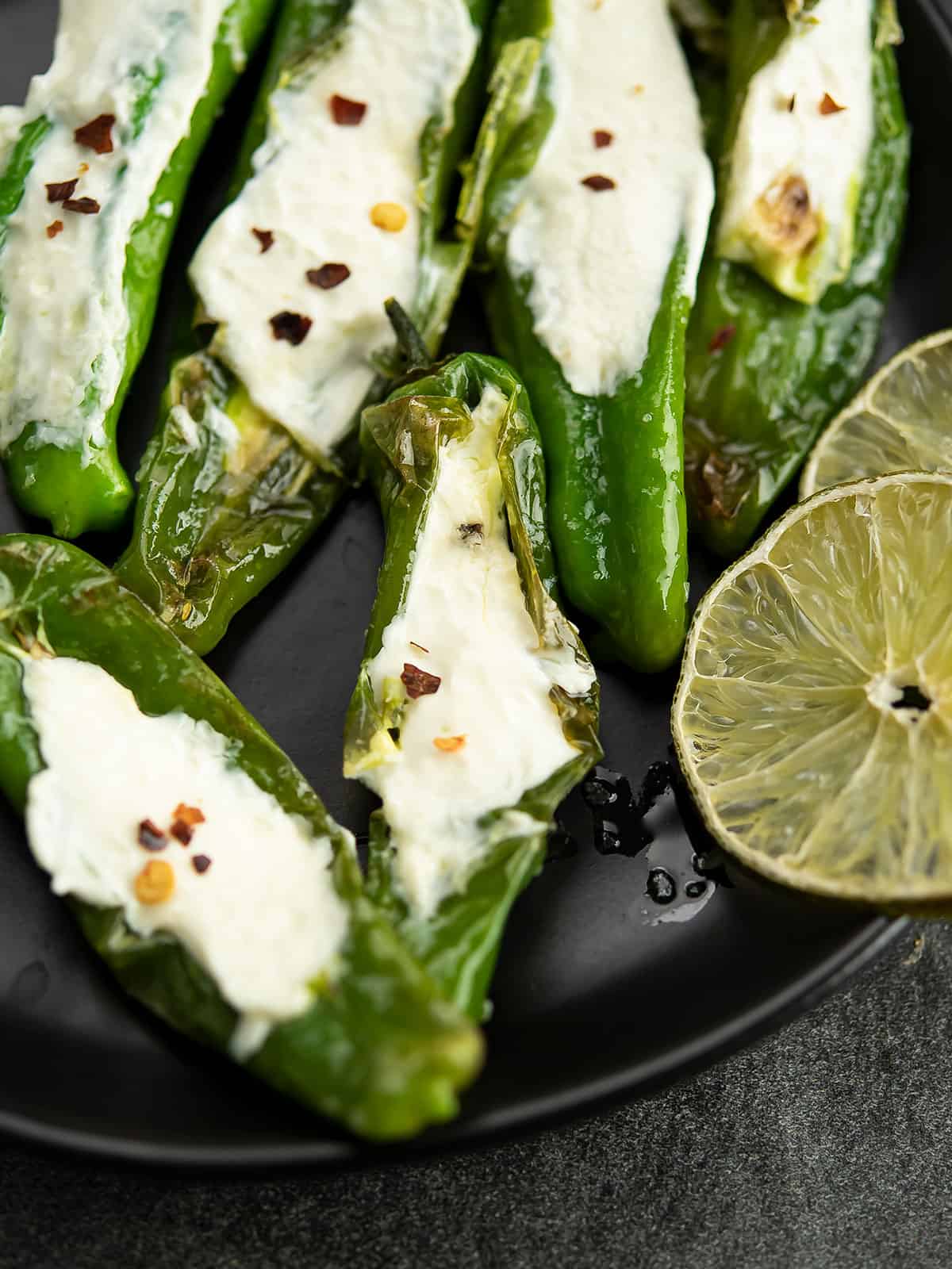 close up view of cream cheese stuffed Shishito peppers in a plate served red pepper flakes