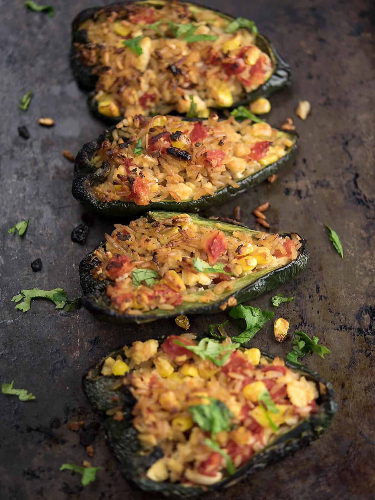 Colorful tofu stuffed peppers topped with herbs on a white plate.