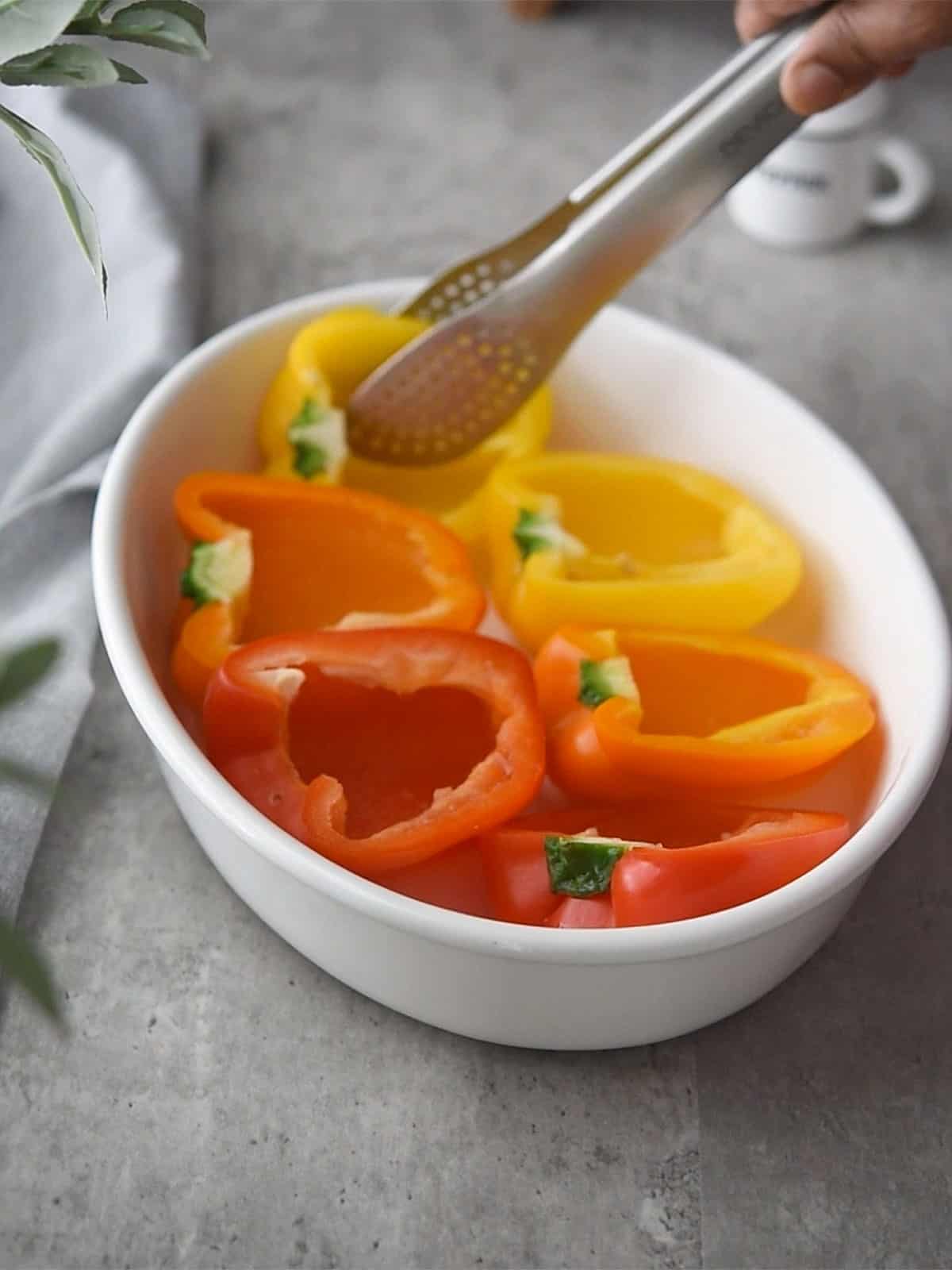 Prepping bell peppers by removing tops and seeds for stuffing.