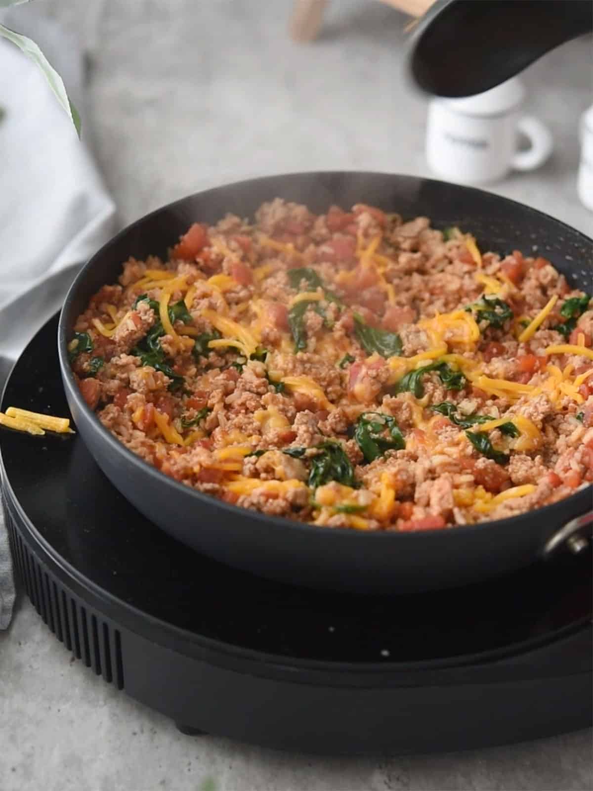 Mixing filling ingredients: diced tomatoes, spinach, rice, and spices in a bowl.