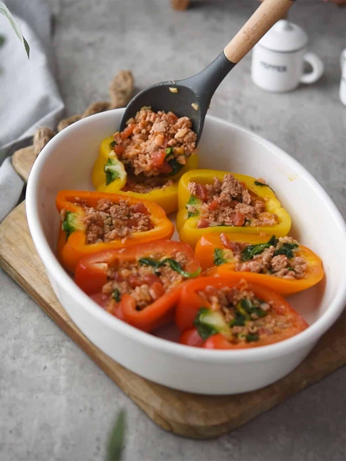 Assembling stuffed peppers by packing the turkey mixture tightly into each pepper.