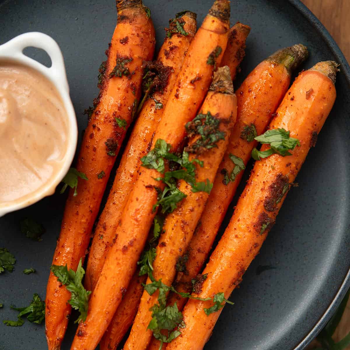spicy roasted carrots served in a plate with a spicy dipping sauce