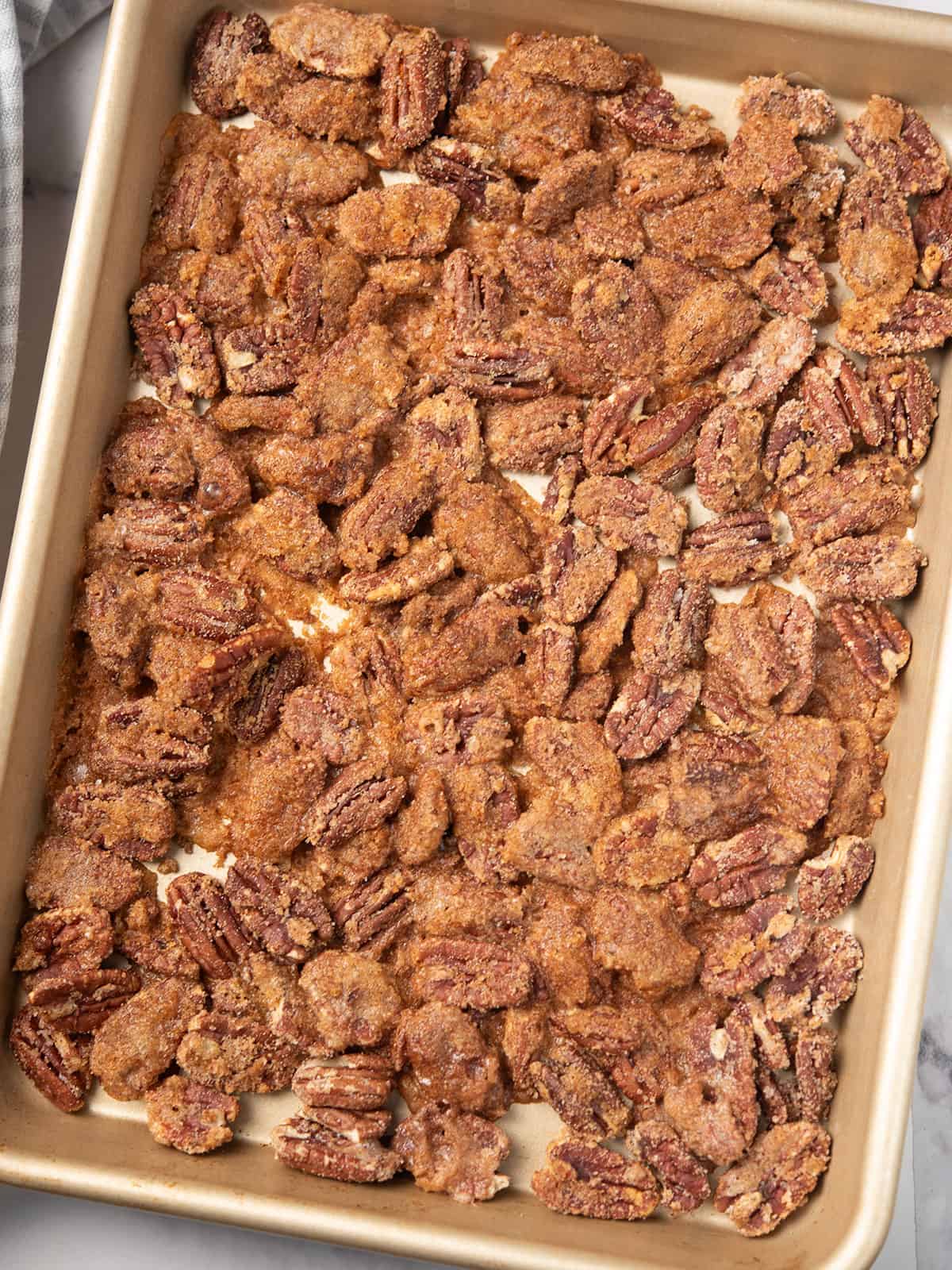 Cooling spicy candied pecans on a baking sheet.