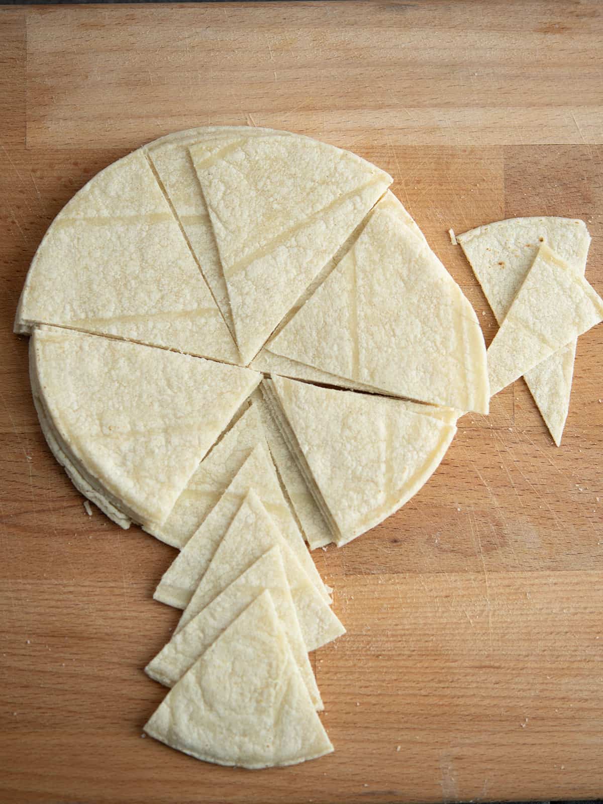 Cutting tortillas into triangles with scissors.