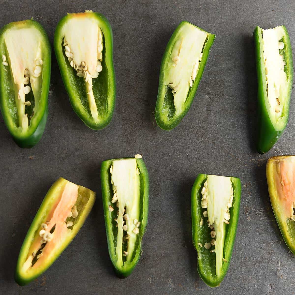 Cut jalapenos ready for stuffing on a cutting board