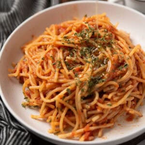 spicy spaghetti served in a white bowl for the dinner with parsley and olive oil