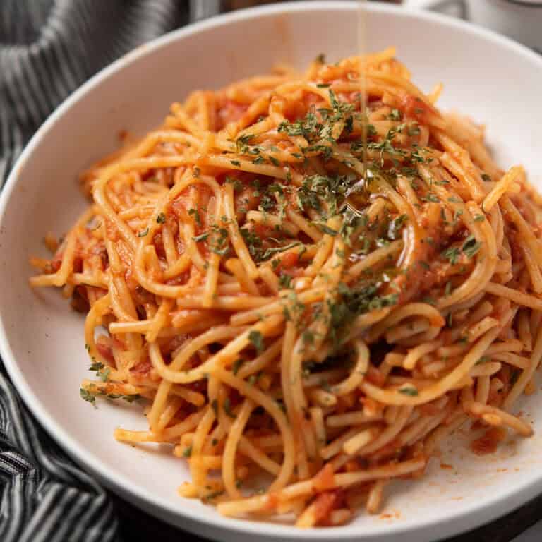 spicy spaghetti served in a white bowl for the dinner with parsley and olive oil