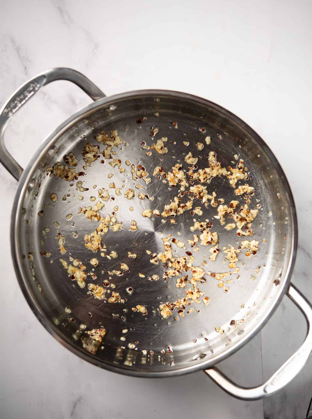 Minced garlic and chili flakes sizzling in olive oil.