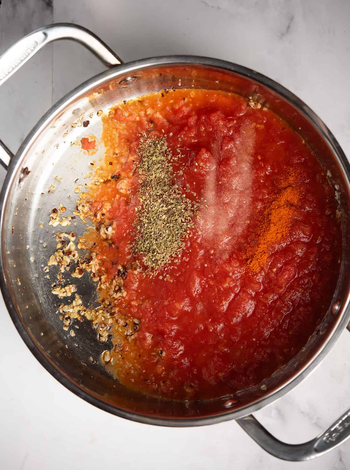 Crushed tomatoes added to the sautéed garlic in a pan.
