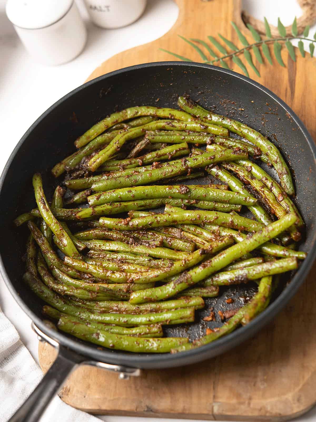 Cajun green beans served in a skillet, garnished cajun seasoning