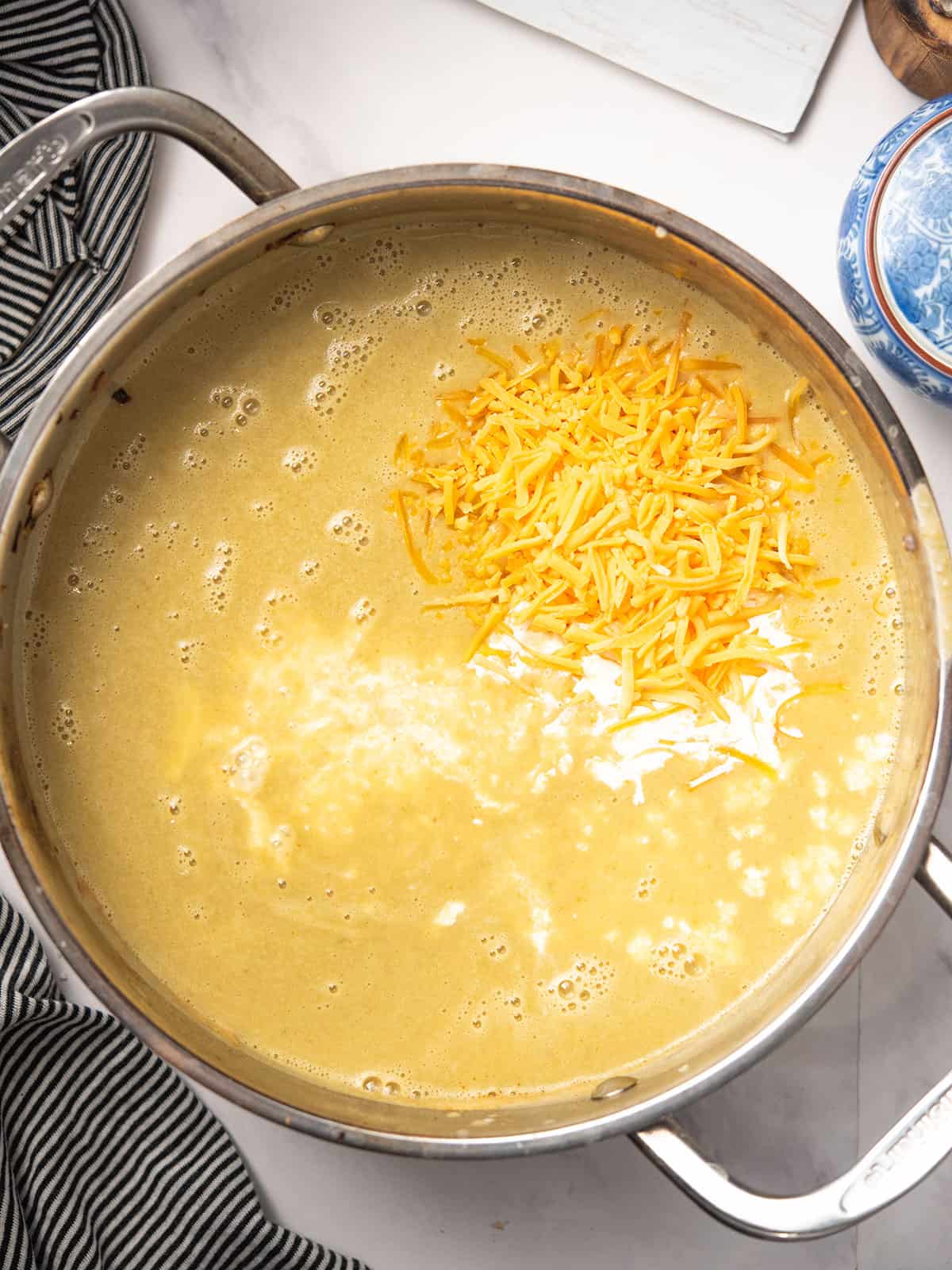 Simmering soup in a pot, adding cream, milk, and cheese