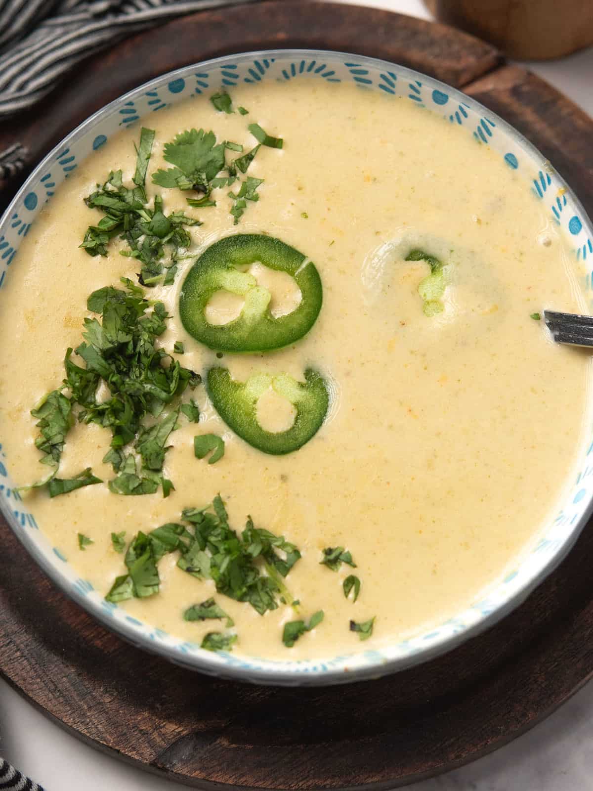 Creamy jalapeño soup garnished with cilantro and jalapeno slices.