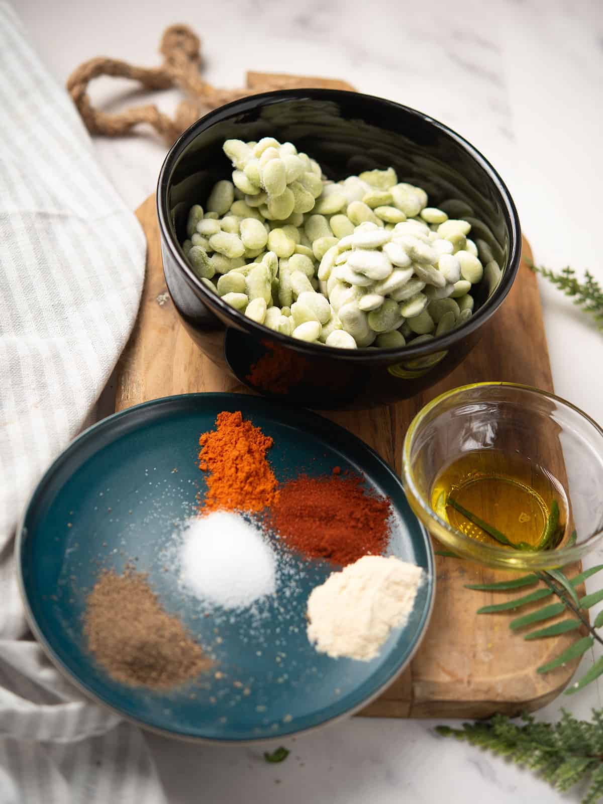 Ingredients for roasted lima beans: frozen lima beans, olive oil, spices, and parsley.