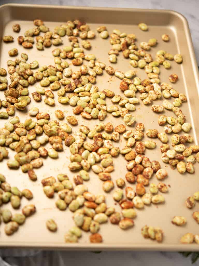 Seasoned lima beans spread in a single layer on a baking sheet.