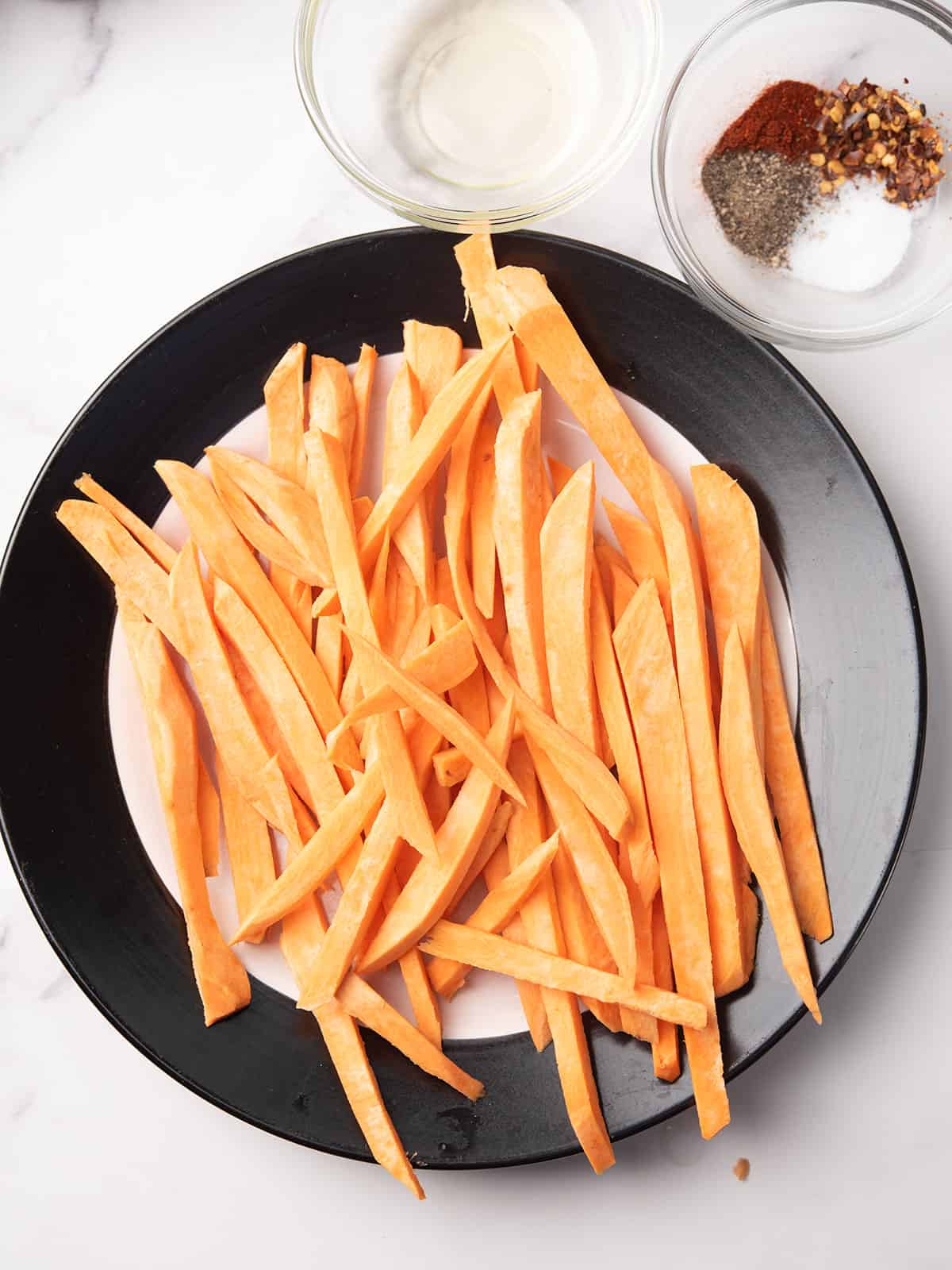 Ingredients for spicy sweet potato fries laid out on a kitchen counter.