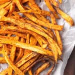 Close-up of spicy sweet potato fries garnished with seasoning.
