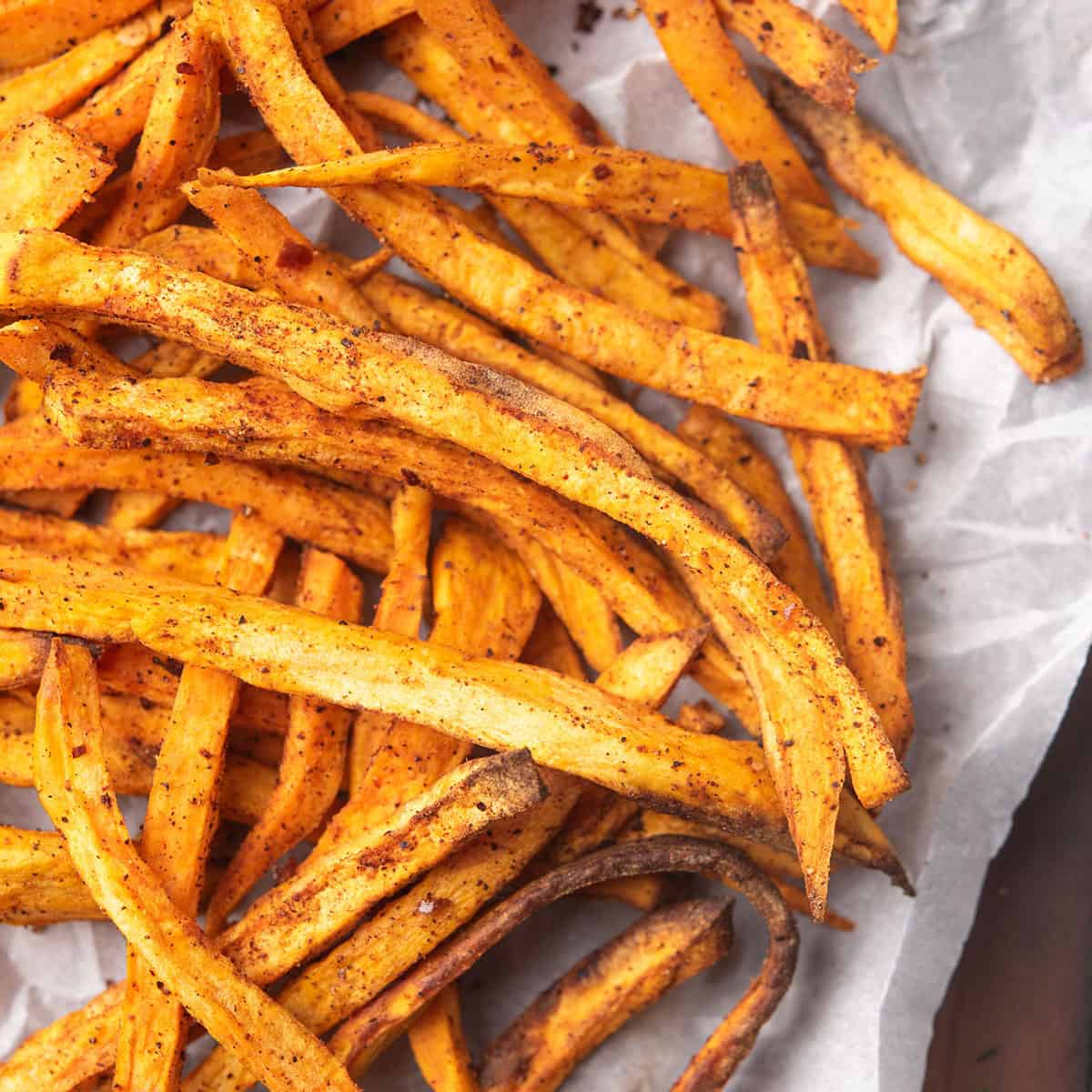 Close-up of spicy sweet potato fries garnished with seasoning.