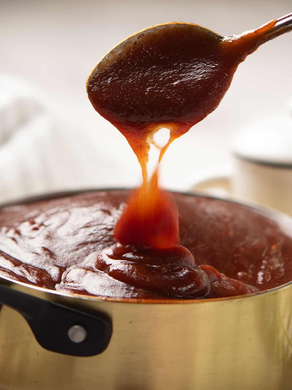 Pouring finished Sriracha BBQ Sauce into an airtight container.