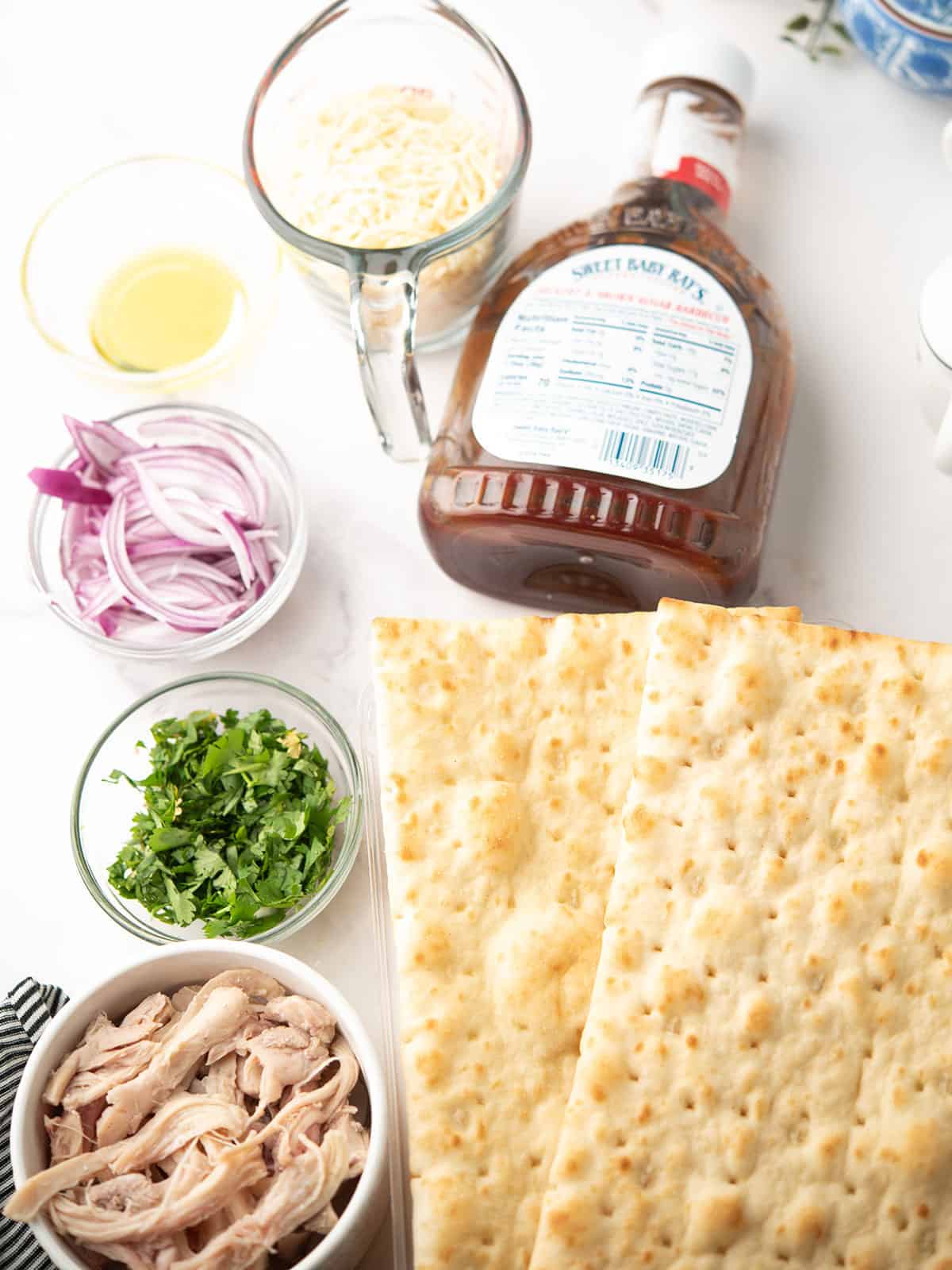 the ingredients for the bbq chicken flatbread assembled over the kitchen counter