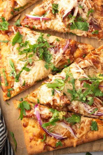 bbq chicken flatbread served over the wooden plank and garnished with cilantro leaves