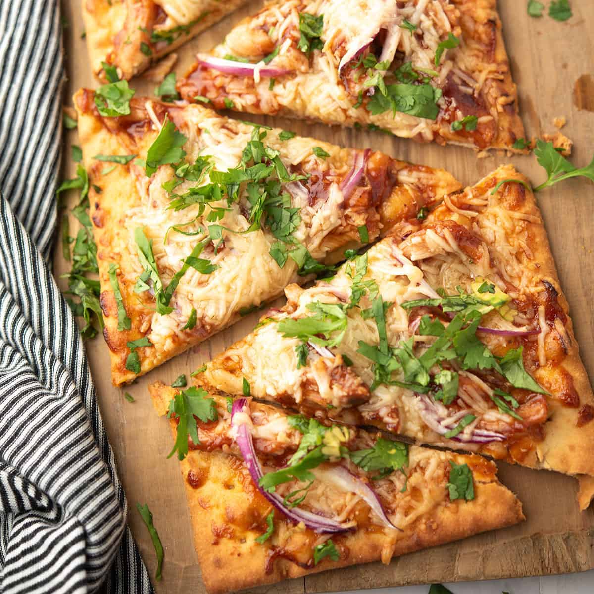 bbq chicken flatbread served over the wooden plank and garnished with cilantro leaves
