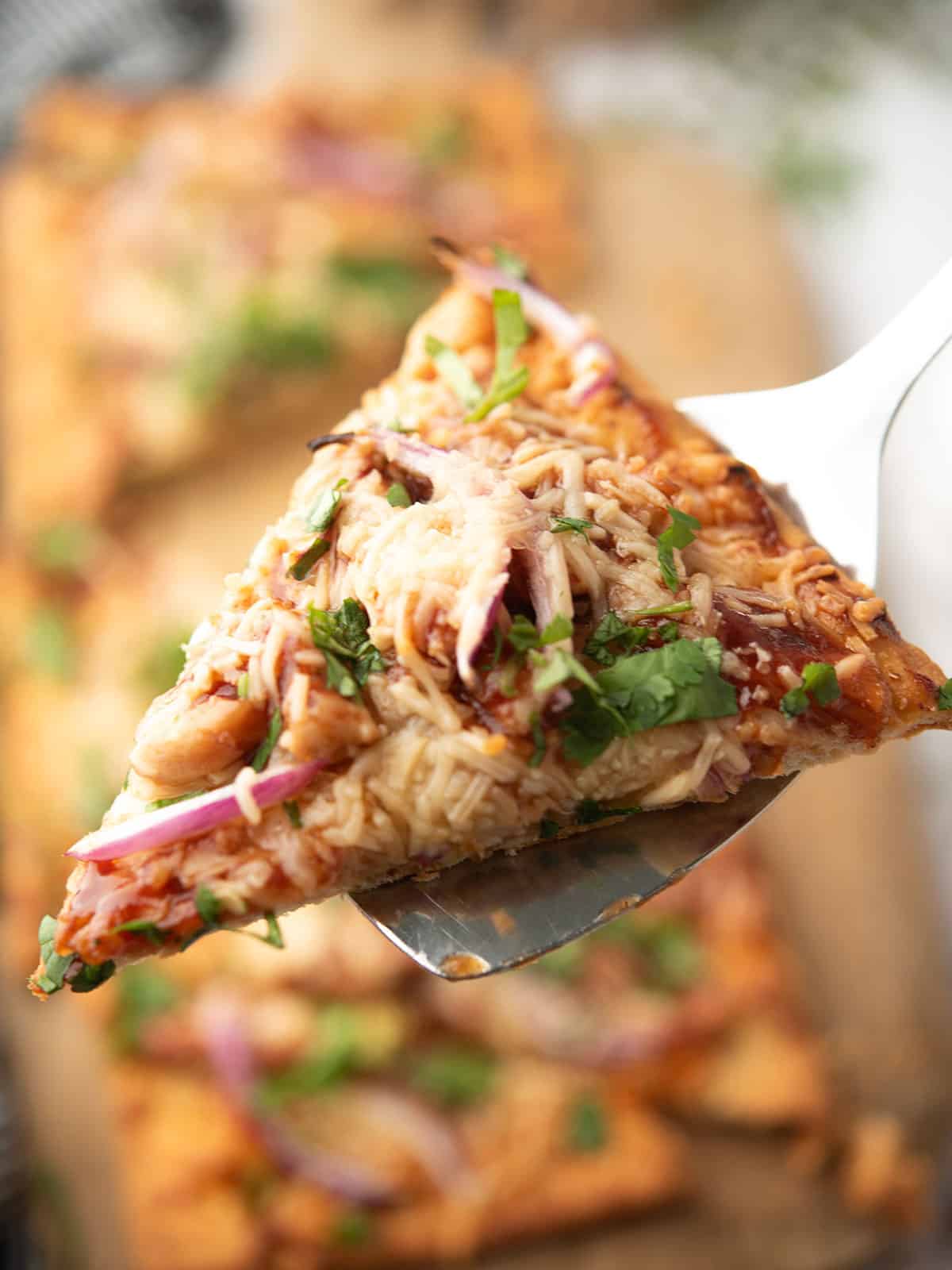 a single bbq chicken flatbread slice in the ladle that's ready to eat