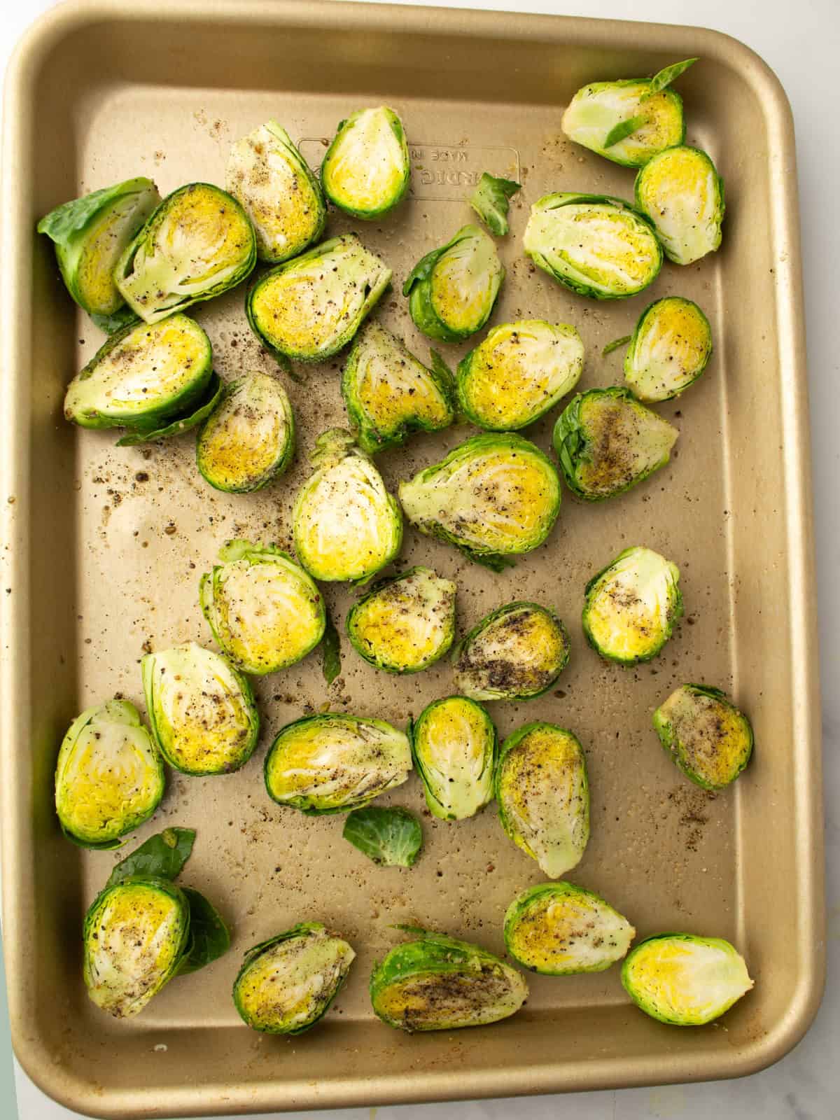 Brussels sprouts tossed with olive oil, salt, and pepper, and arranged cut side up on a baking sheet.
