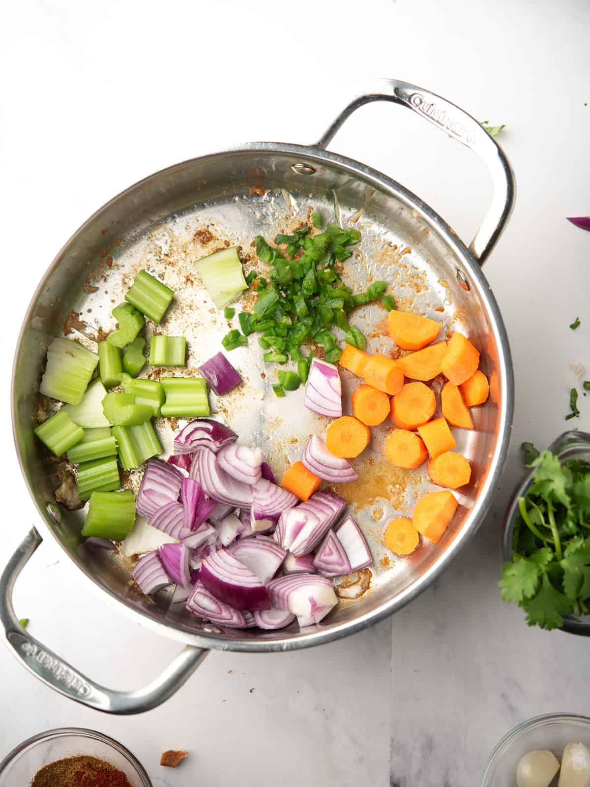 Sautéing onion, carrot, celery, and jalapeño in a pot for soup.