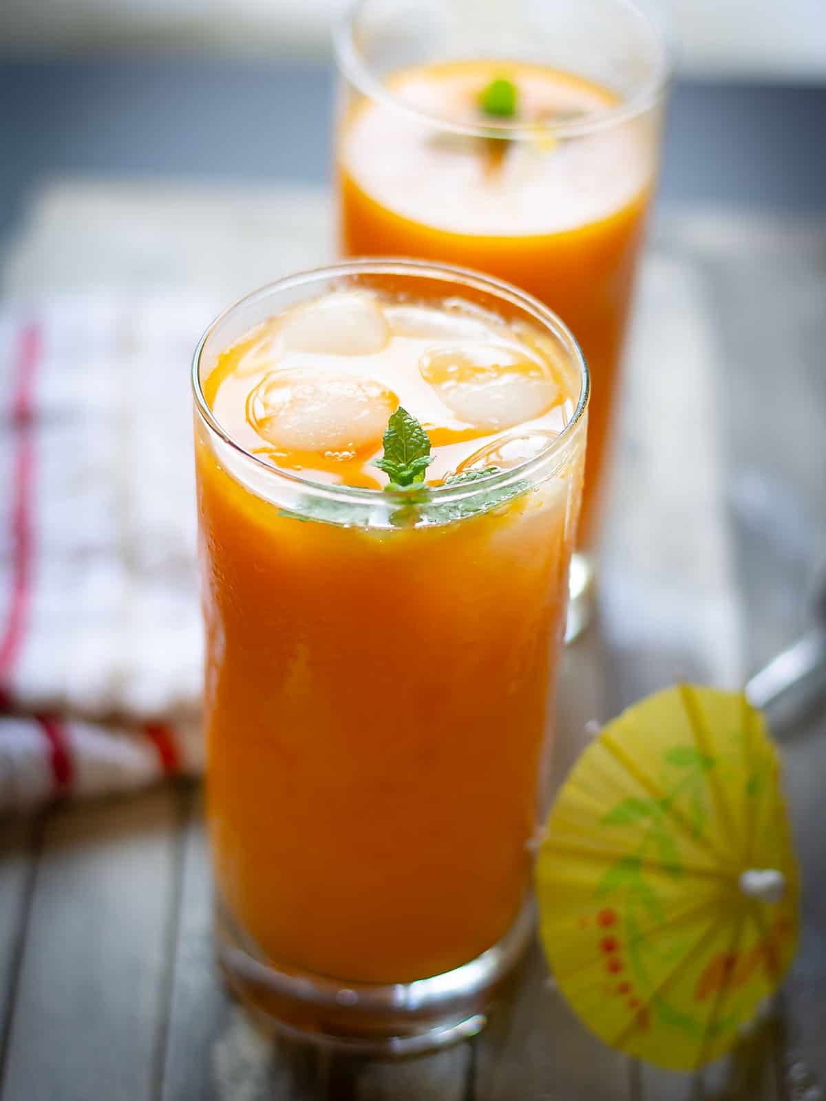 mango juice served in tall glasses with mint leaves as garnish