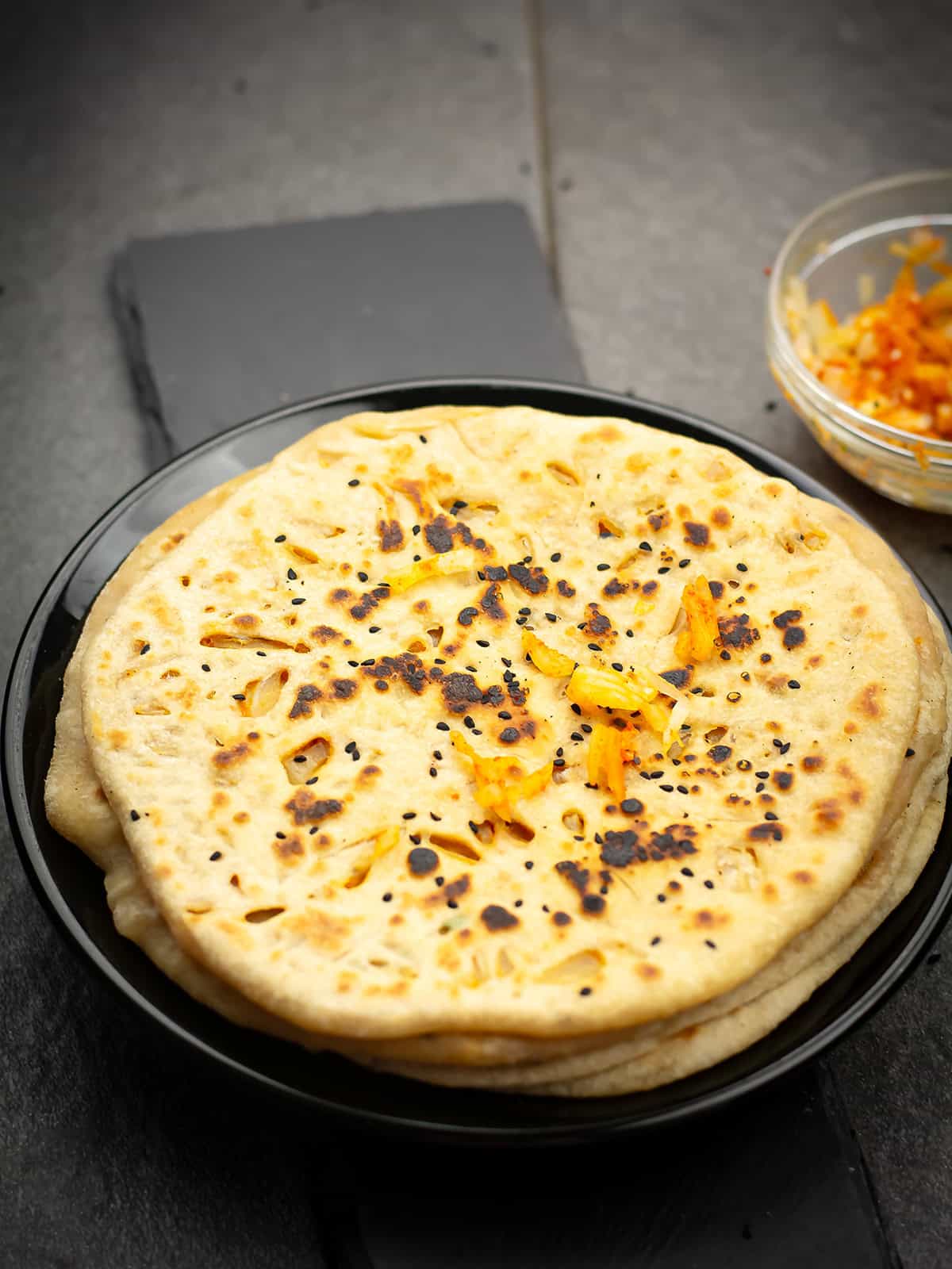 onion kulcha served in a plate with curry on the side