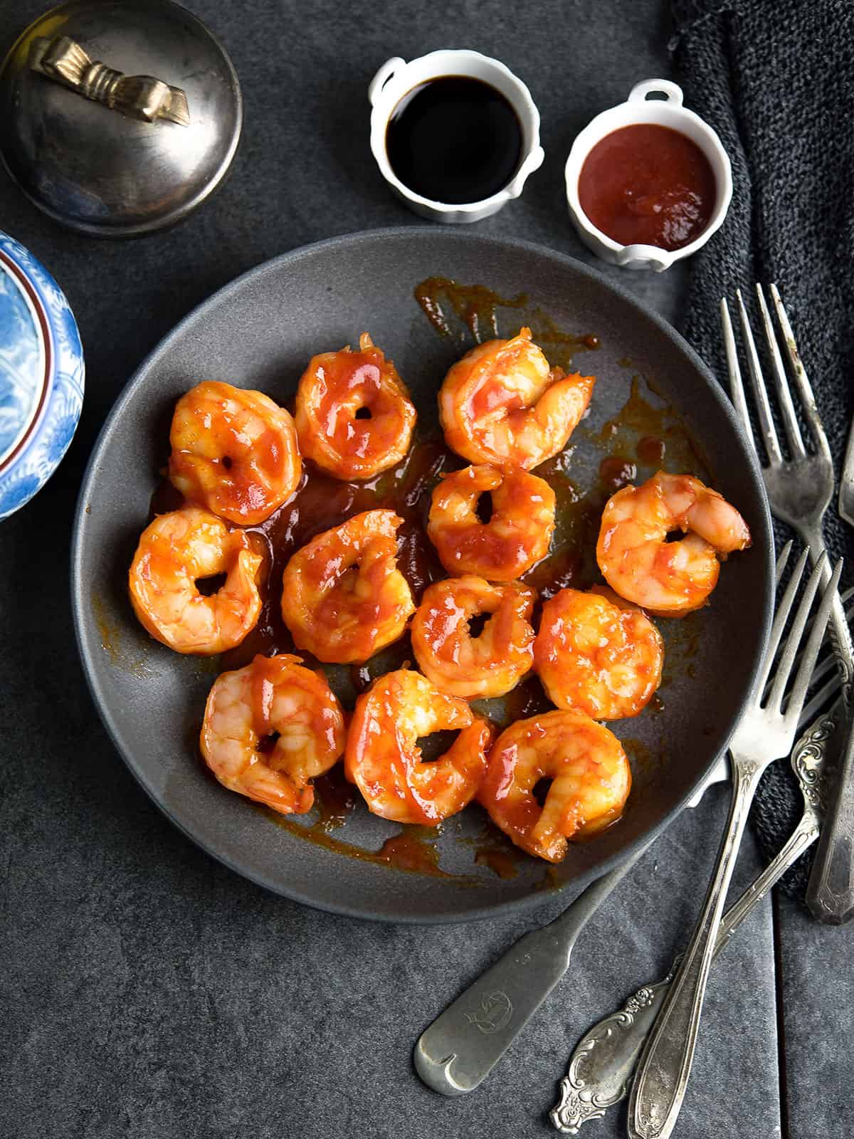 Close-up of Honey Sriracha Shrimp glistening in sauce served in a bowl with fork and dipping sauce